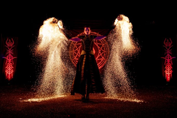 Un artiste de feu jette des étincelles lumineuses dans l'obscurité.